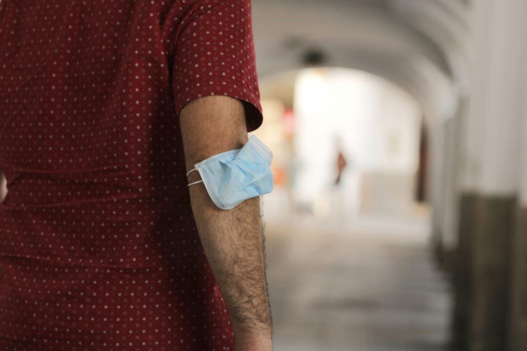 Un hombre lleva la mascarilla en el brazo