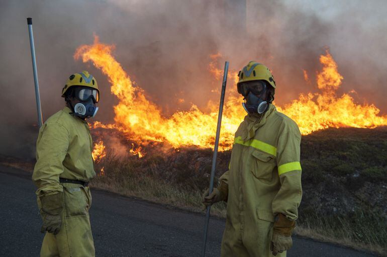 Dos personas durante las labores contra el incendio forestal declarado en Avión (Ourense), en la parroquia de Nieva, en el que trabajan 3 agentes, 12 brigadas, 9 motobombas, 3 palas y 4 helicópteros para evitar que el fuego alcance el núcleo de Porreira. 