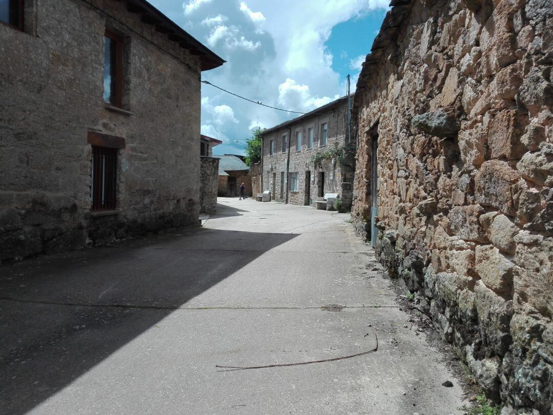 Una calle de Gramedo, con una vecina limpiando la puerta de su casa.