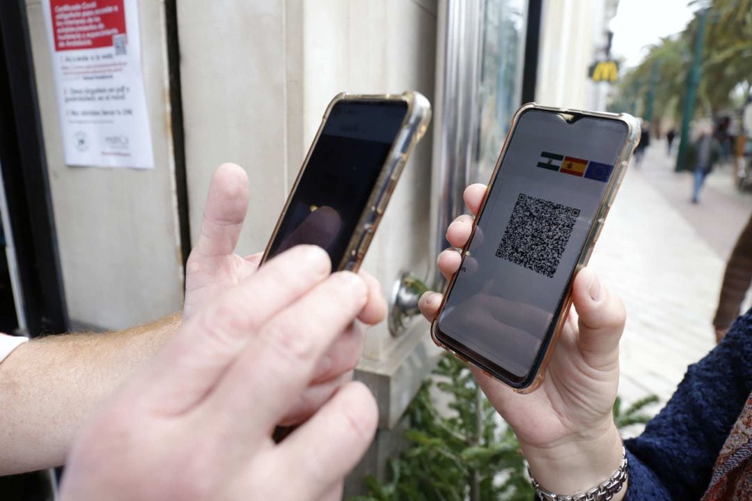 Un camarero pide certificado a los clientes en la puerta de un bar.