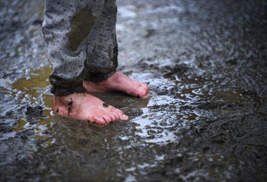 Un niño permanece en pie en el barro en un campo de refugiados cerca de Idomeni (Grecia)