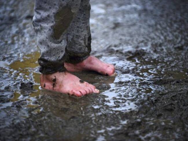 Un niño permanece en pie en el barro en un campo de refugiados cerca de Idomeni (Grecia)