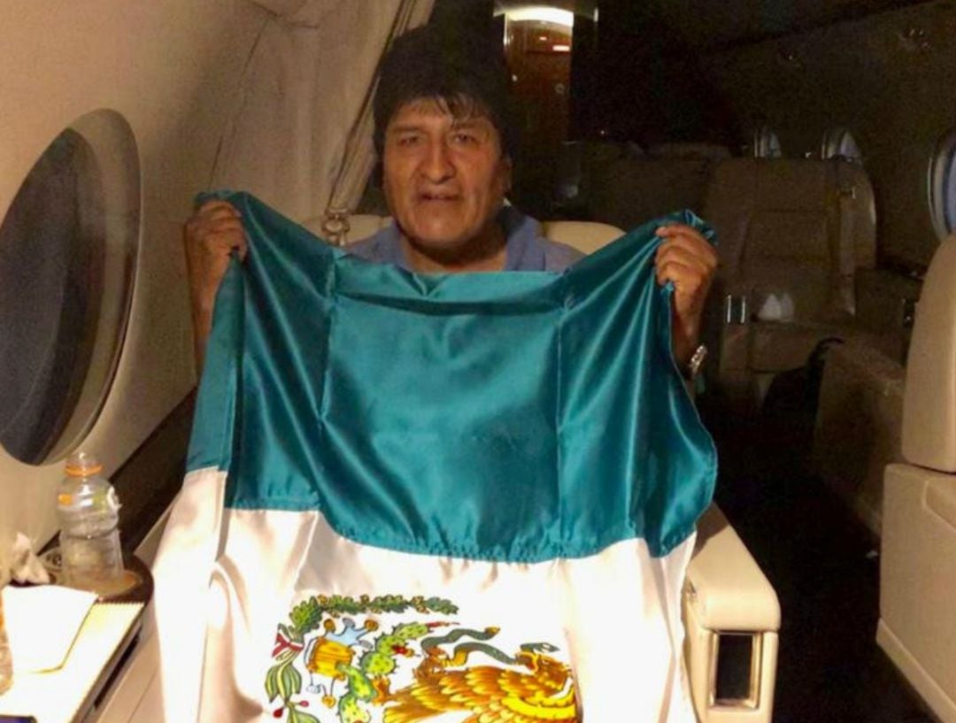 El presidente boliviano Evo Morales sostiene una bandera mexicana a bordo de un avión del gobierno mexicano en una ubicación no identificada el 11 de noviembre de 2019.