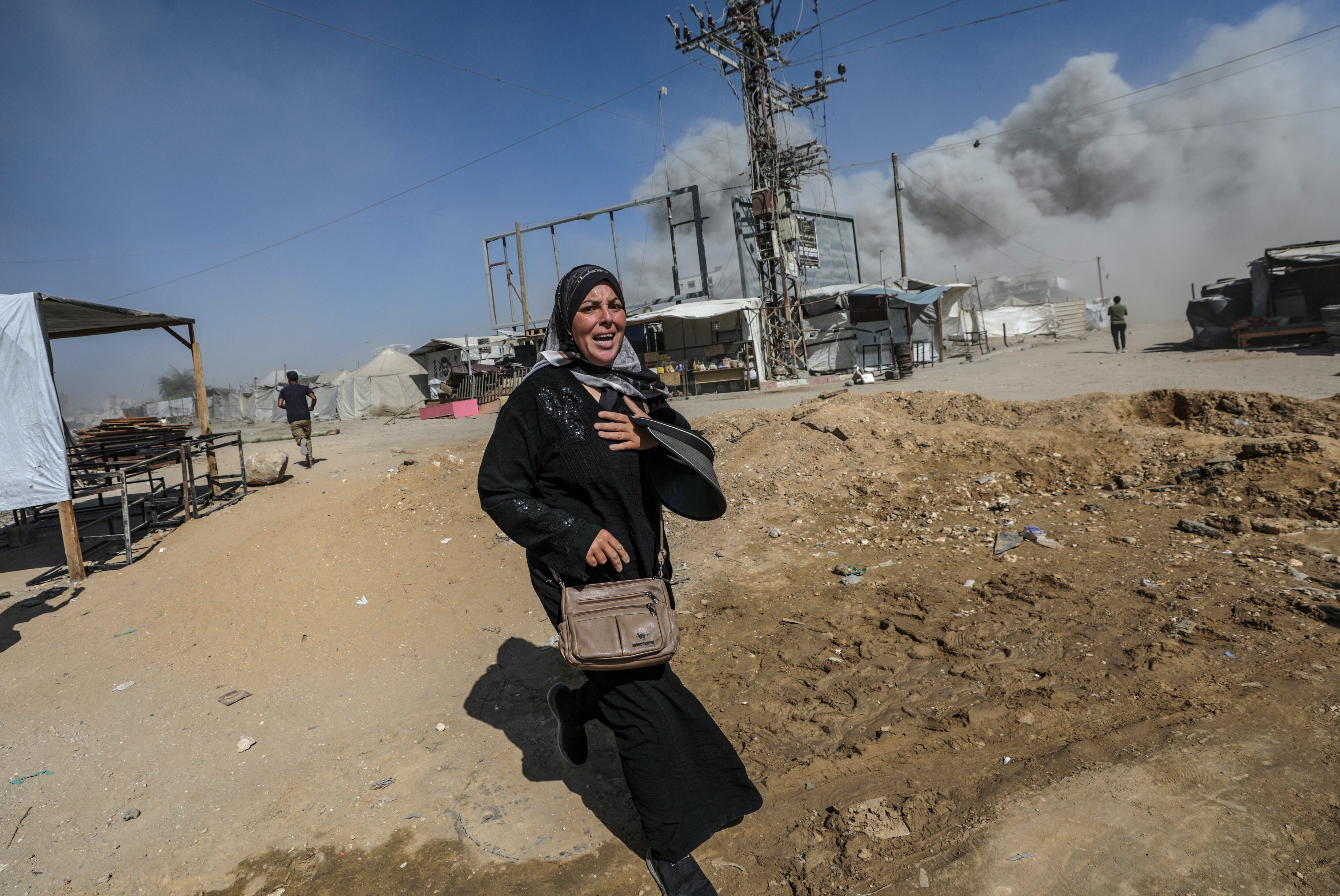 Una dona palestina fuig d'un atac aeri d'Israel a la ciutat de Gaza, ahir dilluns