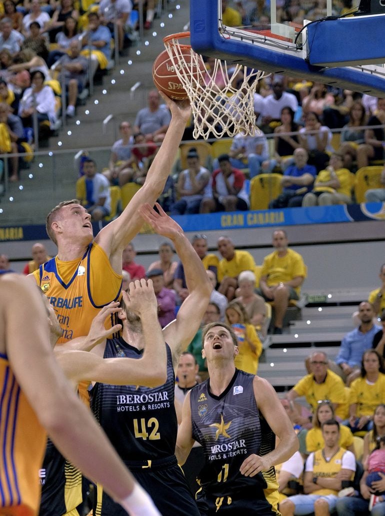 El pivot letón del Herbalife Gran Canaria Anzejs Pasenicks (i) lanza a canasta ante el alero canadiense del Iberostar Tenerife Aaron Doornekamp, durante la primera jornada de la Liga Endesa, que ambos equipos disputaron hoy en el Gran Canaria Arena de la 