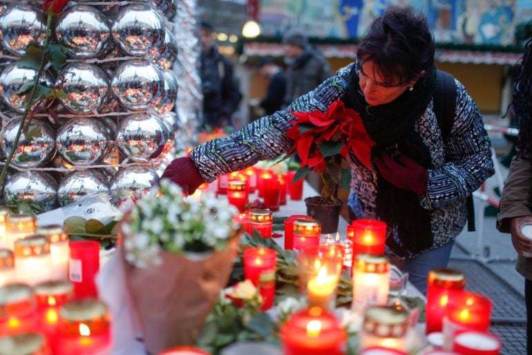 Una mujer enciende una vela en el mercado navideño atacado en Berlín. 