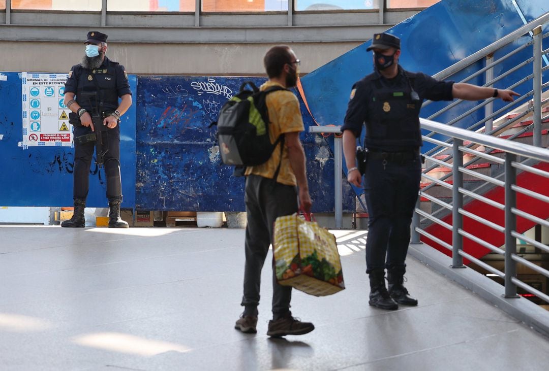 Un agente de la Policía Nacional da indicaciones a un pasajero mientras vigilan la Estación de Atocha, este viernes.