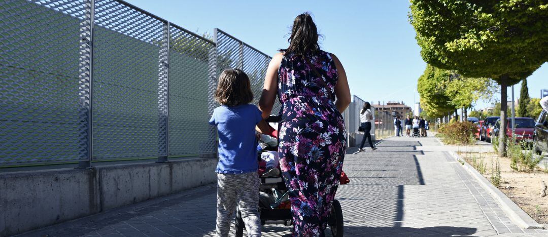 Archivo - Una madre y su hijo empujan el carrito de un bebé en un parque.