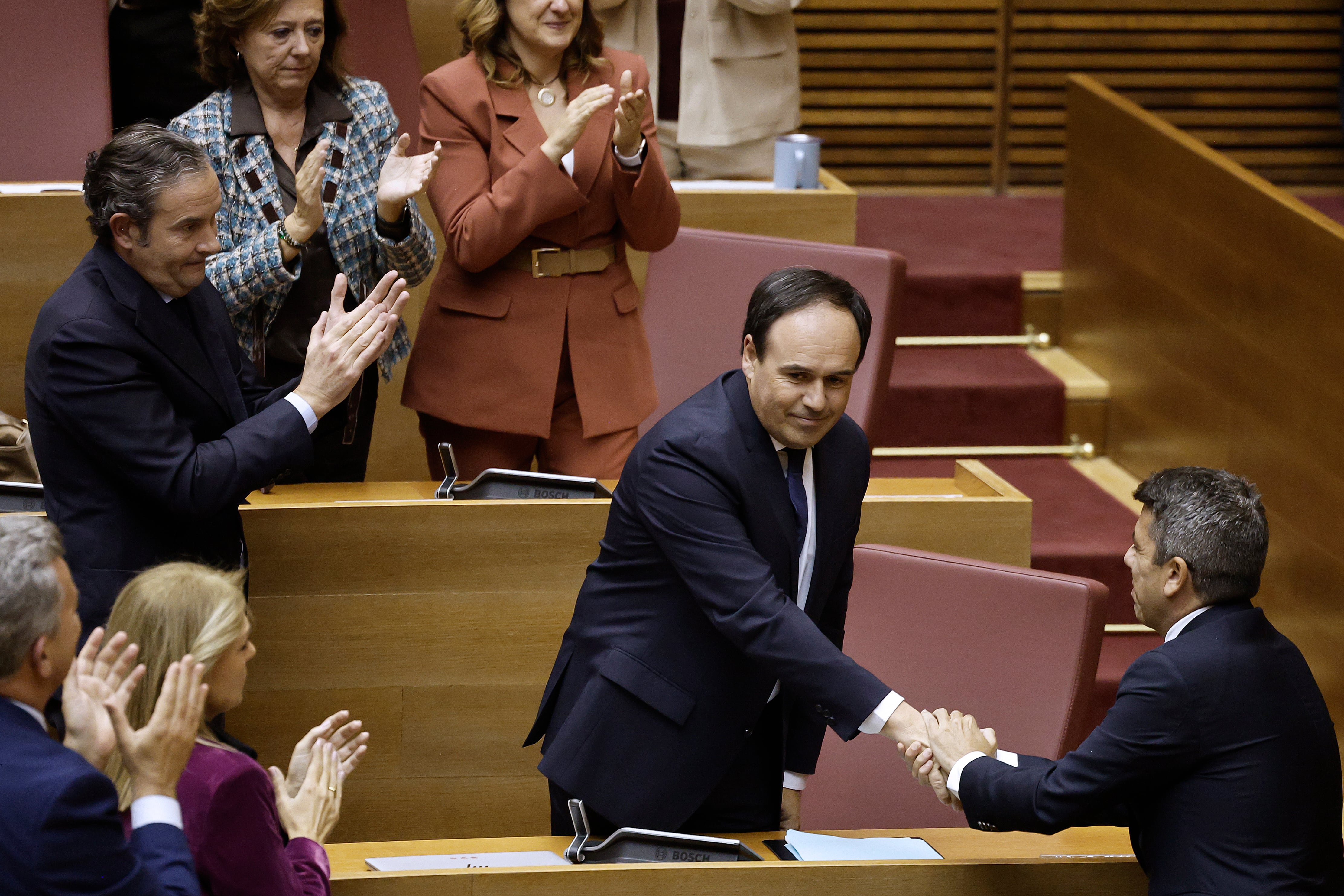 El ya expresident de la Generalitat Carlos Mazón (d) felicita al nuevo president, el secretario general del Partido Popular en la Comunitat Valenciana, Juanfran Pérez Llorca (c), tras salir investido gracias al respaldo de Vox, con cuyos votos ha obtenido la mayoría absoluta que precisaba.