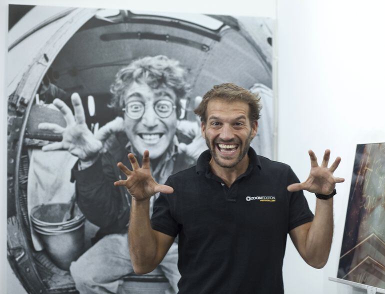 Uno de los propietarios de la tienda Zoomedition posa delante de una foto de César Lucas a John Lennon