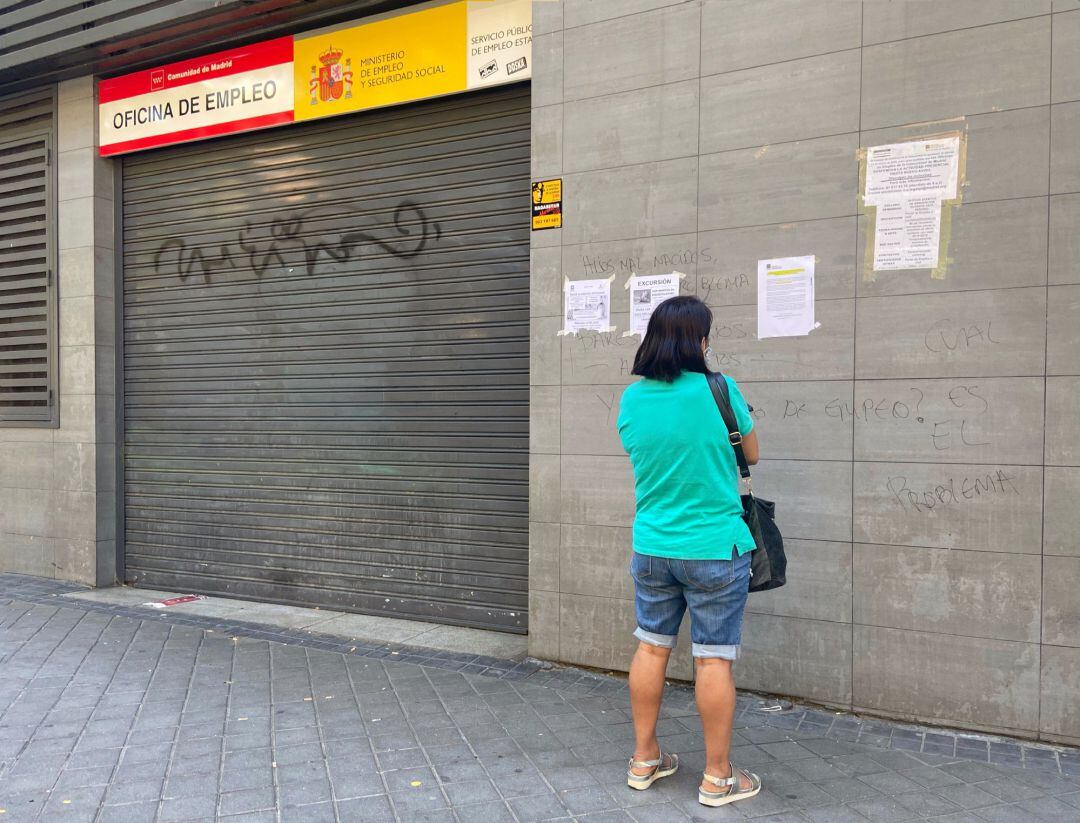 Una persona observa uno de los carteles con instrucciones para hacer trámites por internet colocados en la fachada de una oficina del SEPE