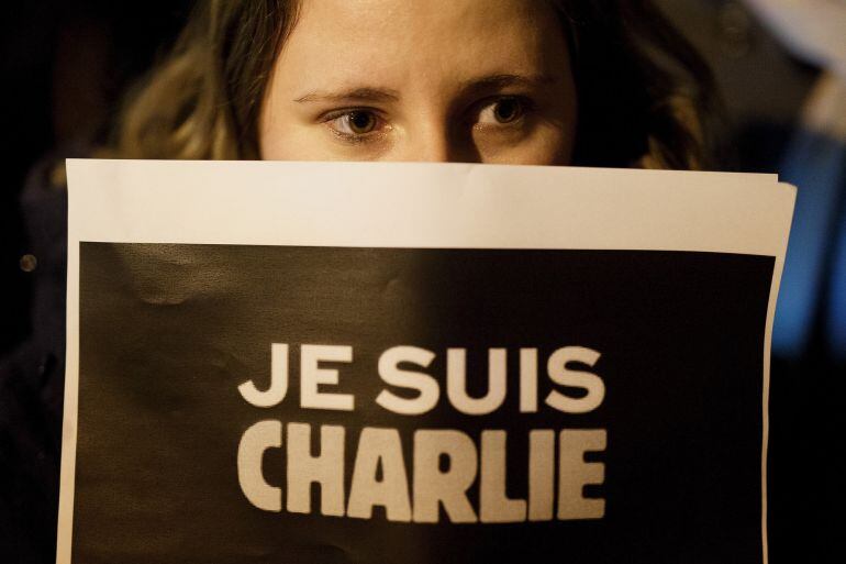 MADRID, SPAIN - JANUARY 07:  A woman holds a placard reading &#039;Je Suis Charli&#039; (I am Charlie) during a gathering of people showing their support for the victims of the terrorist attack at French magazine Charlie Hebdo, in front of the Embassy of France on 