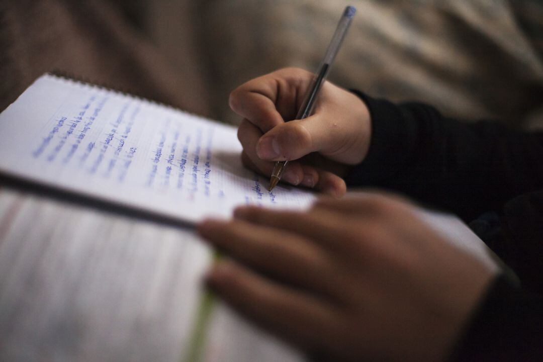 Un niño toma notas en un cuaderno en clase.