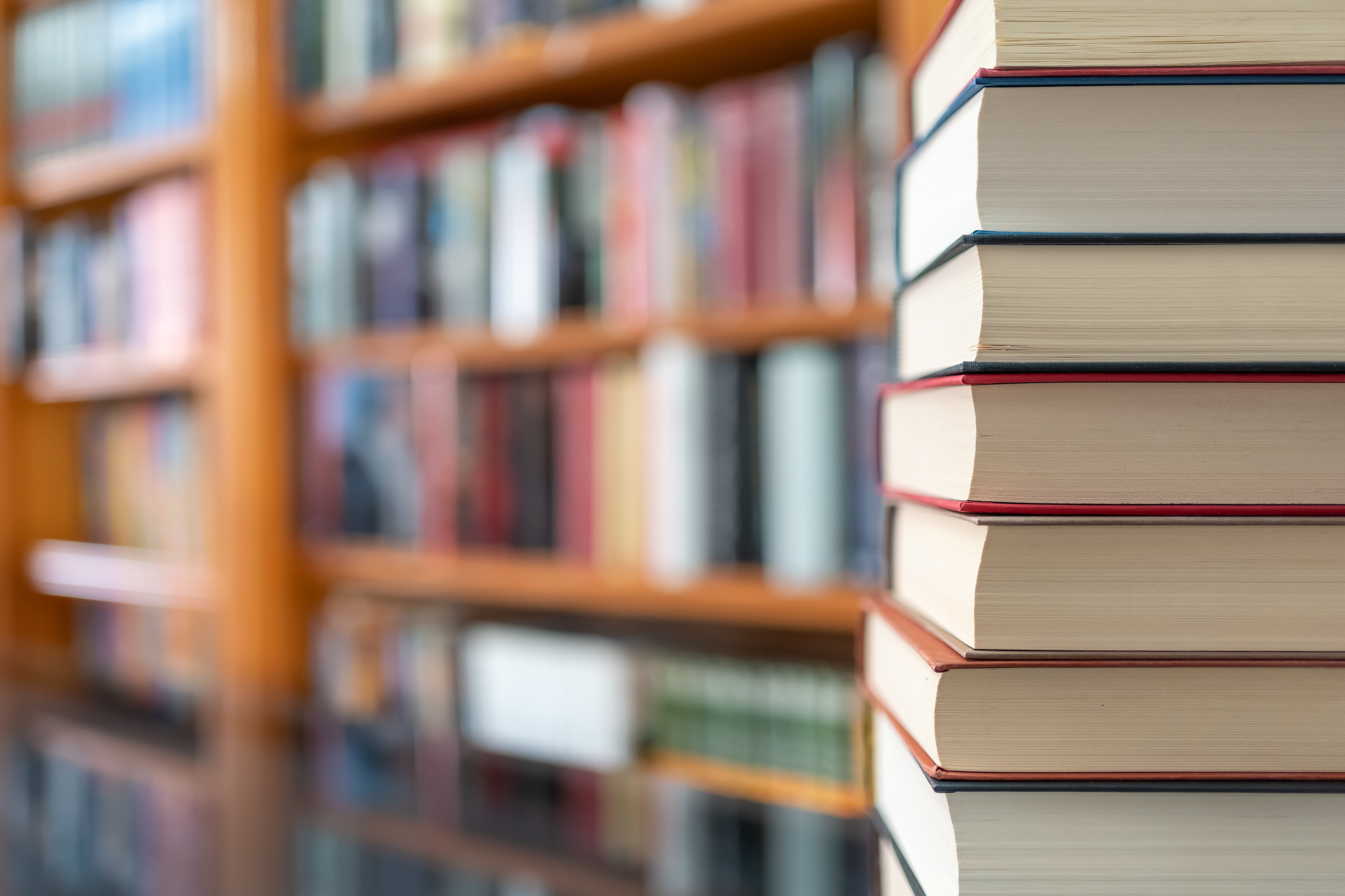 Many books stacked with blurred background of bookstore full of books. Photo with copyspace