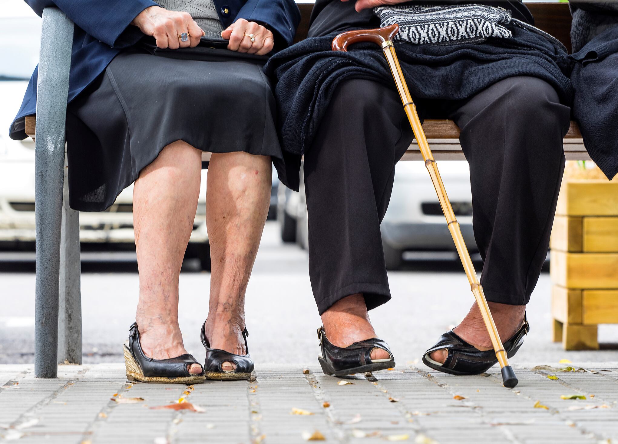 Grupo de mujeres mayores sentadas en un banco en una calle