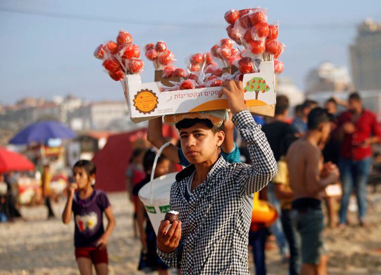 Un chico vende dulces en una playa de la franja.