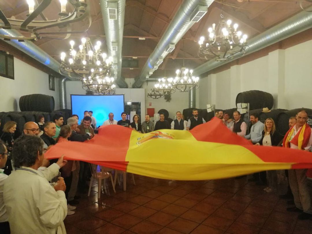 Miembros de Vox, sujetando la bandera de España para cerrar la noche electoral.