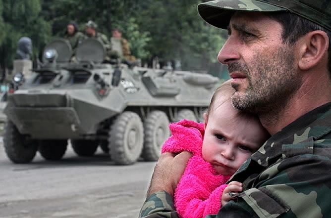 Un militar de Osetia del Sur sostiene a un bebé en sus brazos.