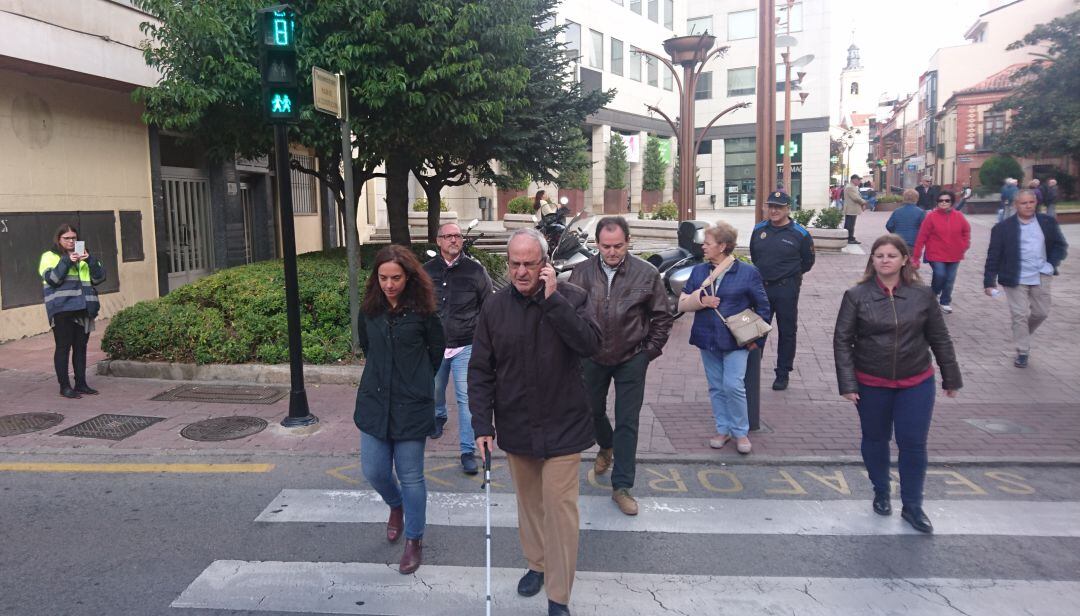 Una persona con discapacidad visual cruzando en el semáforo de la plaza de la Constitución de Getafe acompañado por la alcaldesa