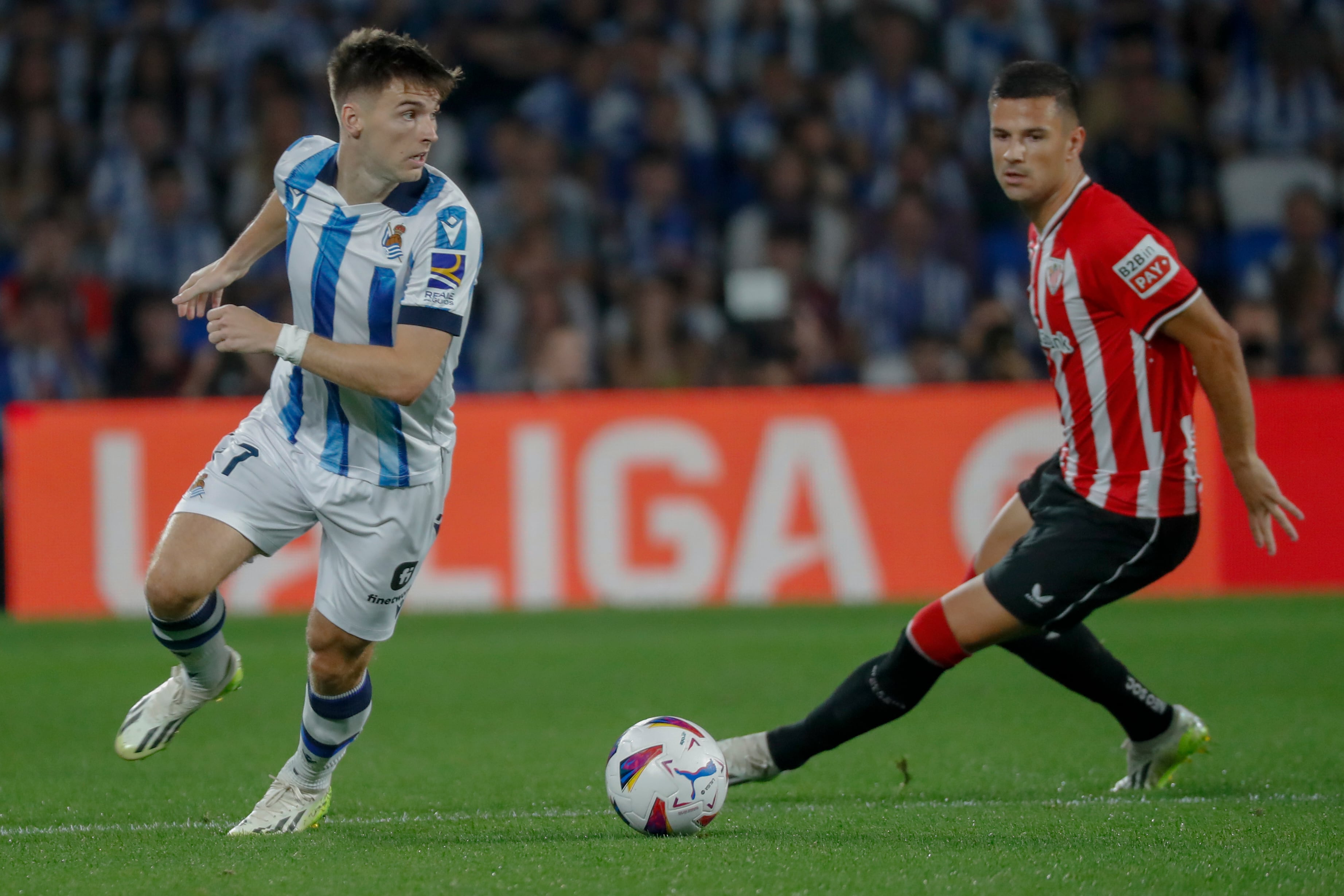 El lateral de la Real Sociedad Kieran Tierney (i) juega un balón ante Gorka Guruzeta, del Athletic, durante el partido de LaLiga que Real Sociedad y Athletic Club disputan este sábado en el Reale Arena, en San Sebastián