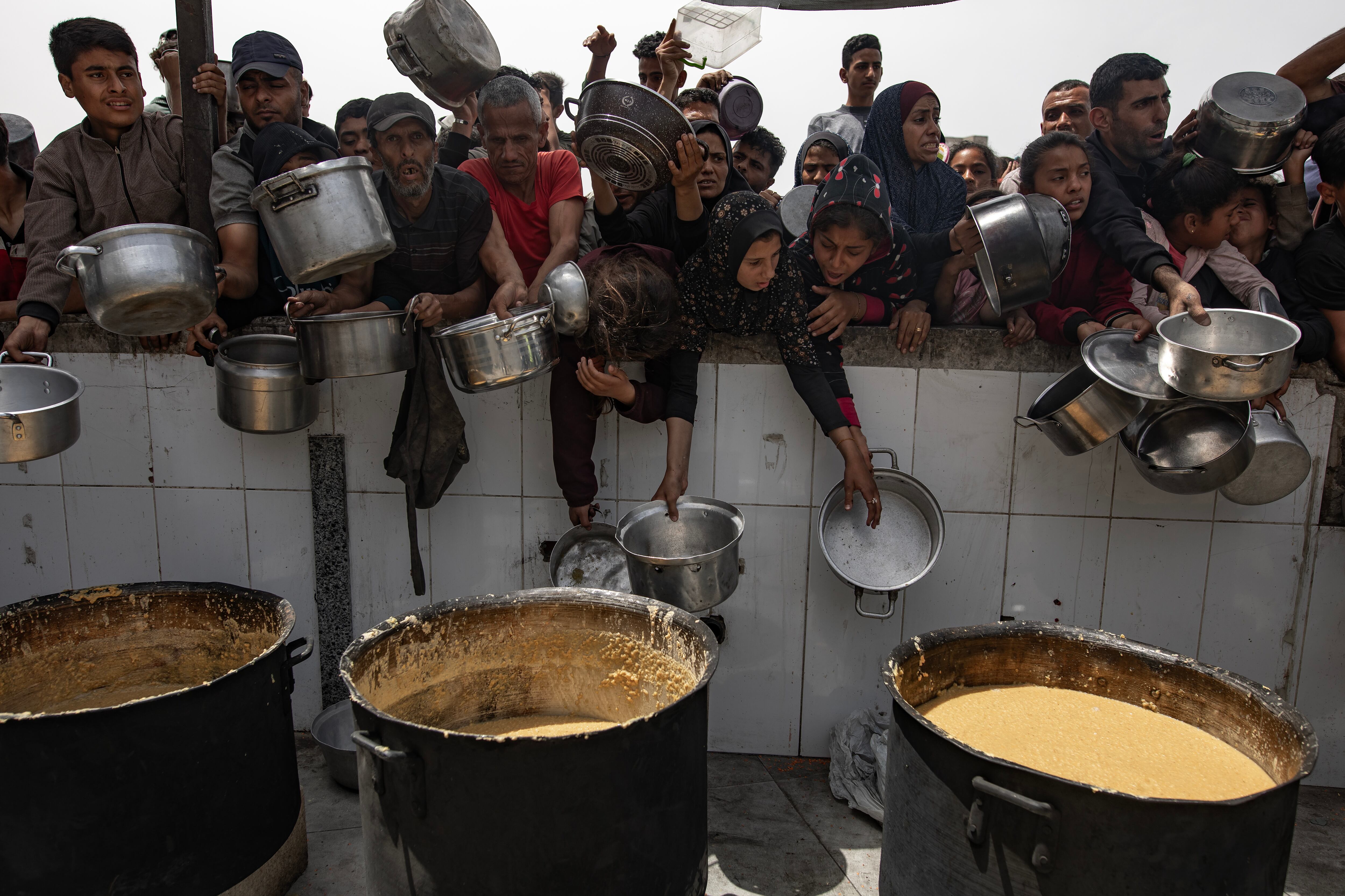 Un grupo de palestinos desplazados hace cola para poder coger comida servida por las organizaciones humanitarias en Jabalia, al norte de Gaza, esta semana. EFE/EPA/HAITHAM IMAD