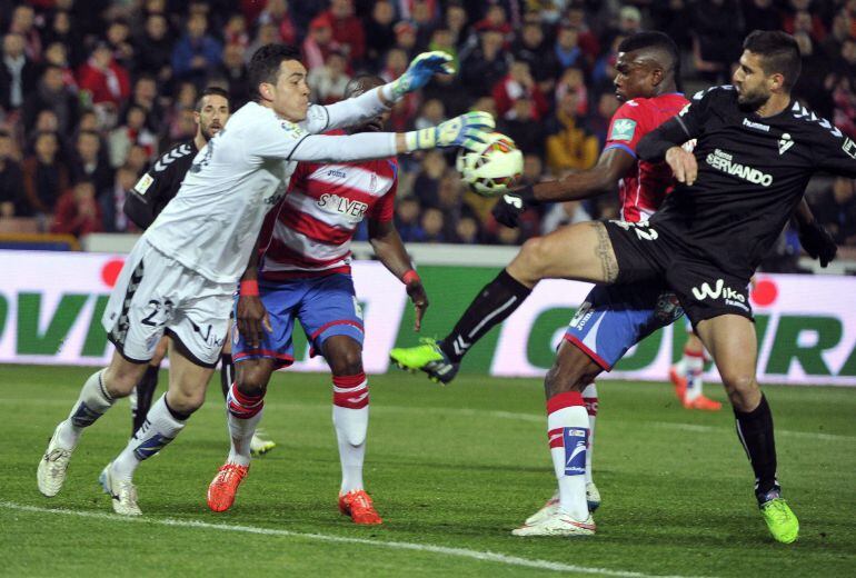 GRA403. GRANADA, 21/03/2015.- El guardameta del Eibar, Jaime (i), intenta despejar un balón ante el delantero mexicano del Granada, John Andrés Córdoba (2d) y su compañero, Raúl Rodríguez Navas, durante el encuentro correspondiente a la vigésimo octava jornada de primera división, que disputan esta noche en el Nuevo Estadio de Los Carmenes, en Granada.