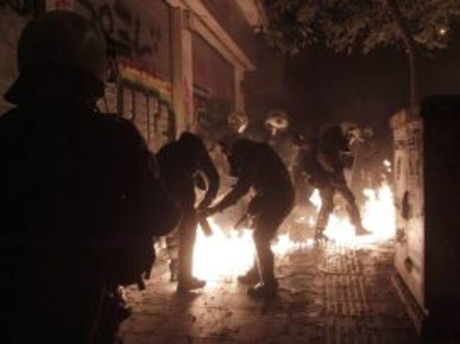 Los agentes antidisturbios tratan de apagar un cóctel molotov lanzado por uno de los manifetsantes.