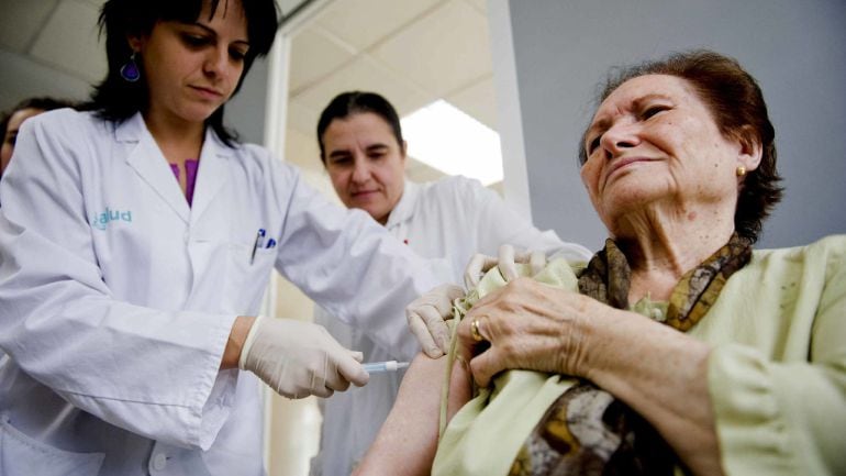 Una enfermera administra una vacuna contra la gripe a una paciente. 