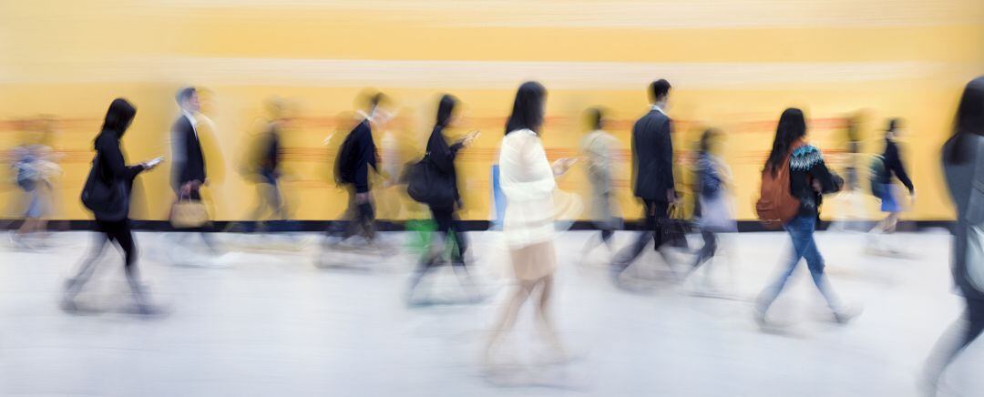 Trabajadores comprobandio sus teléfonos mientras caminan. 