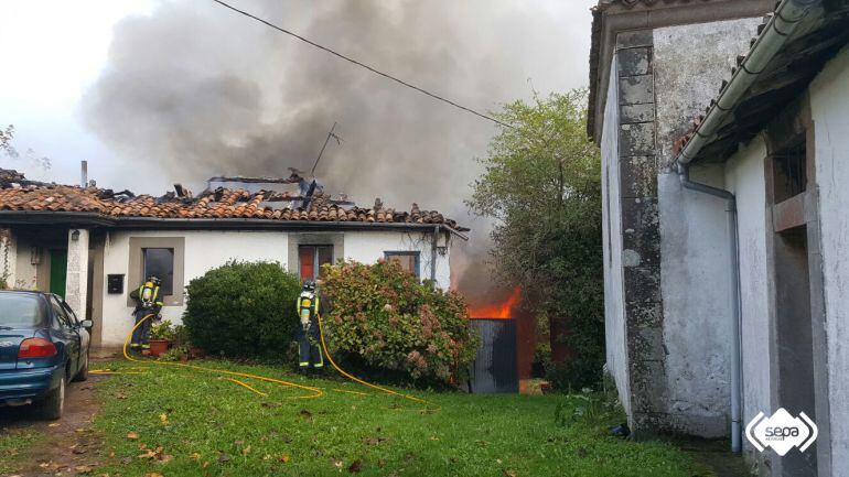 Los Bomberos trabajan en la extinción de las llamas en la vivienda en el pueblo de Cazanes.