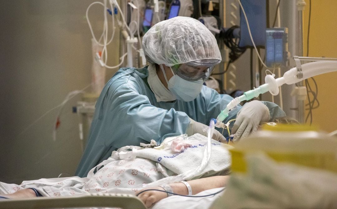 Una profesional sanitaria cuida de un paciente ingresado en una UCI.