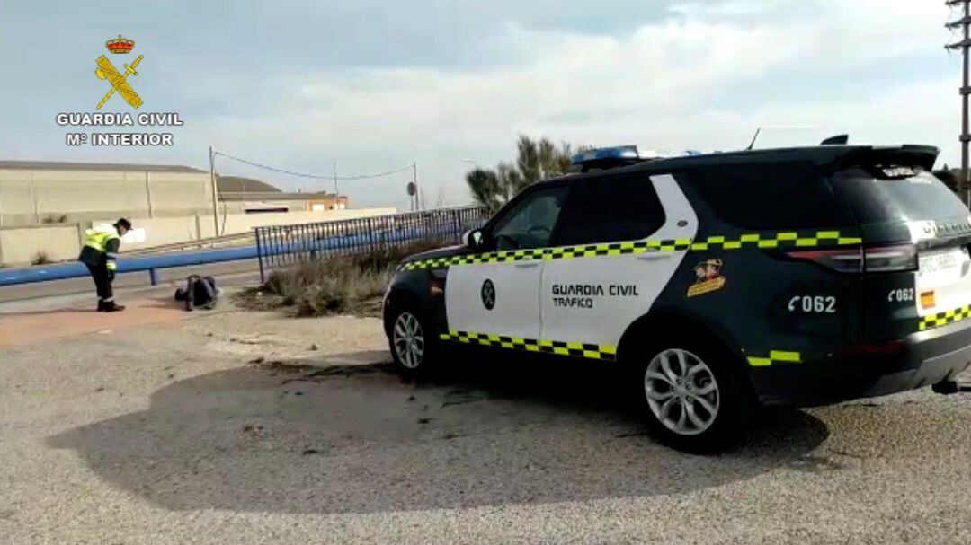 Un agente de la Benemérita auxilia a un hombre sin hogar tumbado en la carretera que dio positivo en coronavirus  