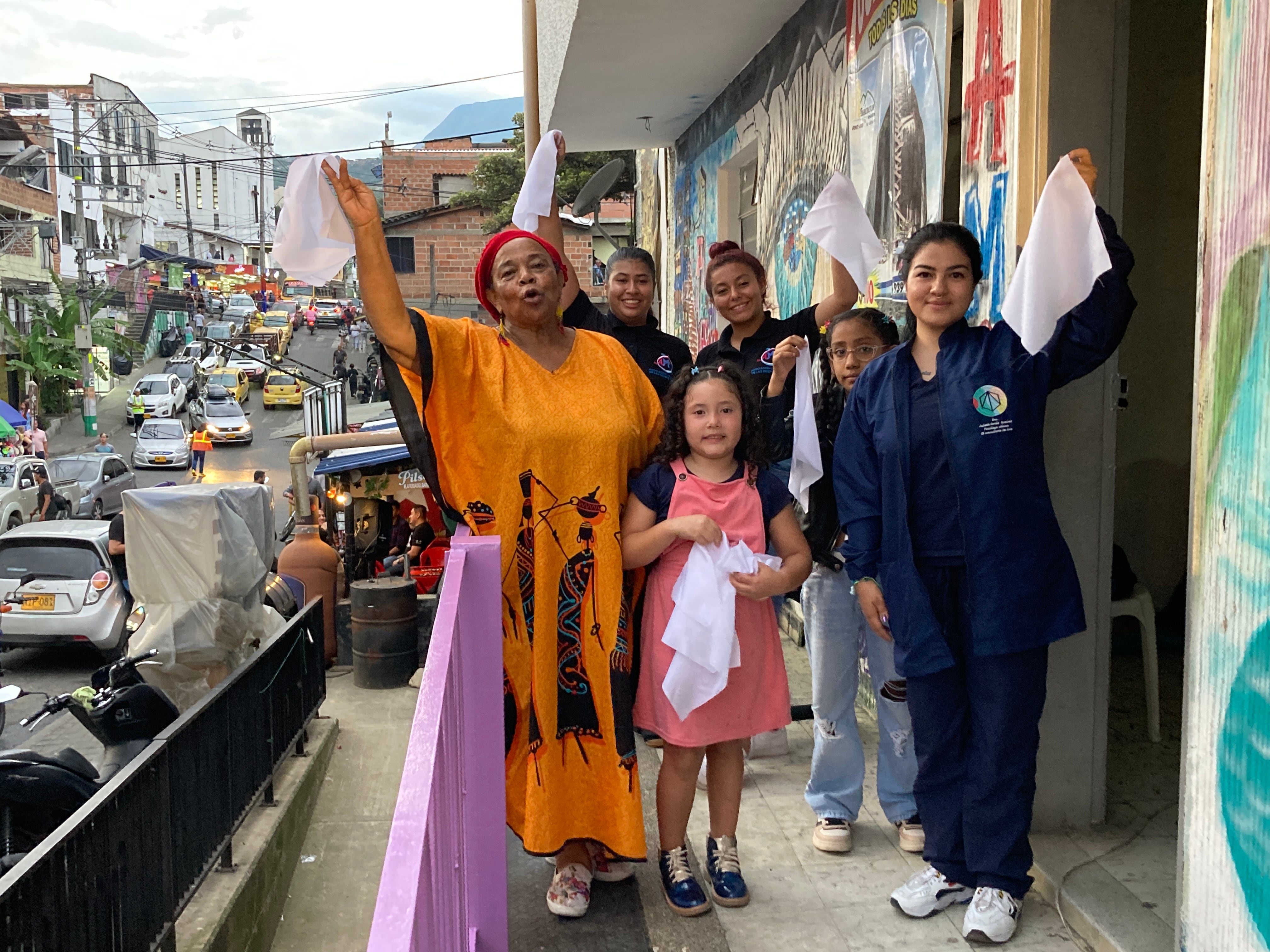 Yula Cortés, con uniforme azul, junto la Socorro Mosquera, figura clave en el movimiento social del barrio, y un grupo de chicas a las puertas del centro que dirige en la Comuna 13