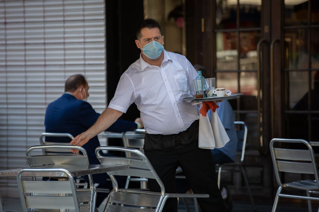 Un camarero sirve en la terraza de un bar.