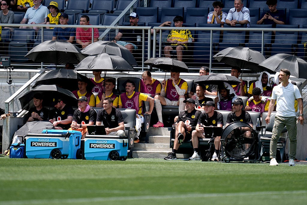 Los jugadores del Borussia Dortmund en el banquillo con paraguas
