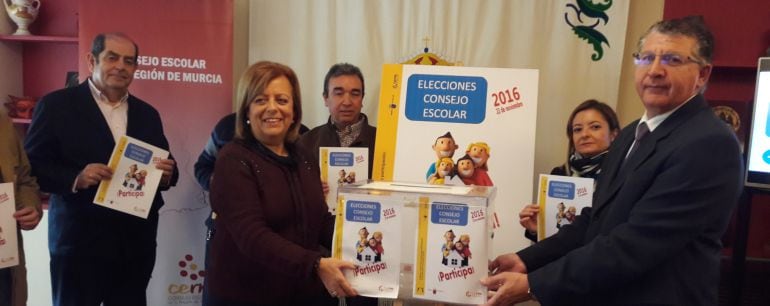 La consejera de Educación, junto a Juan Castaño, presidente del Consejo Escolar de la Región, sostienen la urna y animan a votar en el proceso electoral que se celebra mañana en 490 centros.