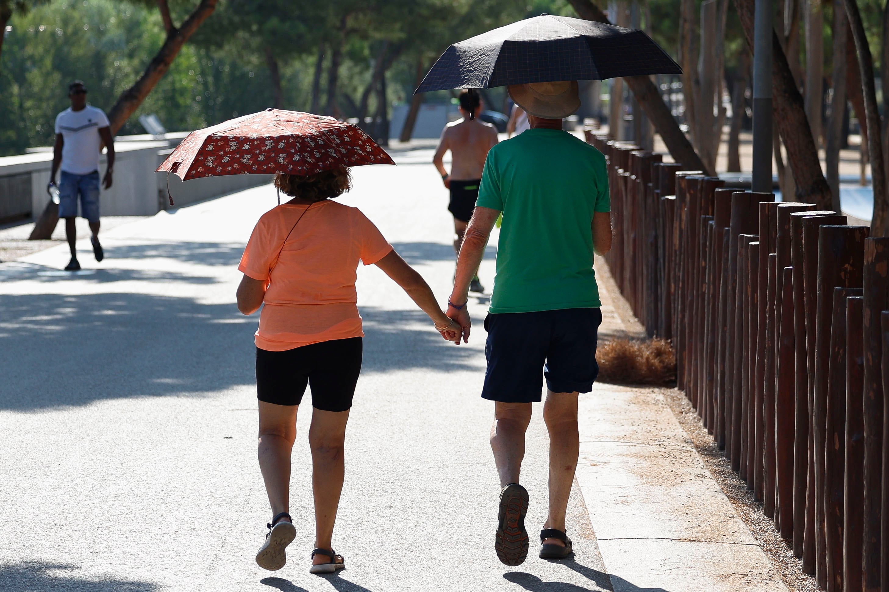 Una pareja pasea protegida por paraguas esta mañana en la que el calor ya aprieta en Madrid.