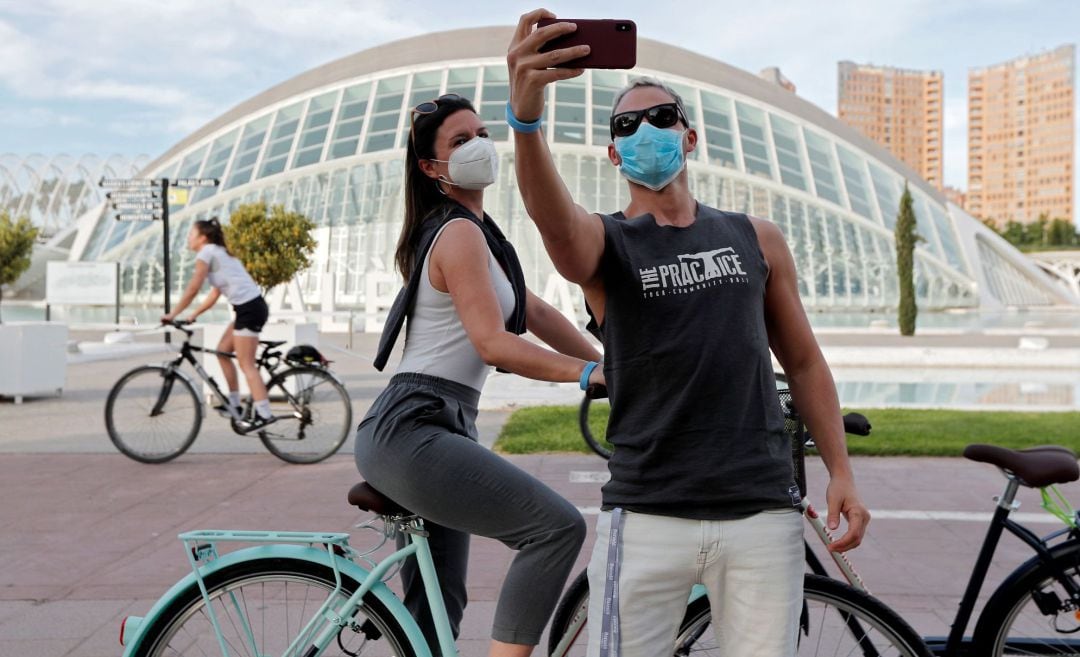 Una pareja de ciclistas se hace una foto ante el Hemisferic en el antiguo cauce del Turia de València