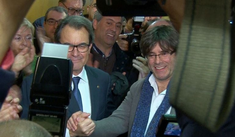 Apretón de manos entre Artur Mas y Carles Puigdemont después de que el presidente en funciones de la Generalitat diera a conocer el acuerdo de investidura entre Junts pel Sí y la CUP.