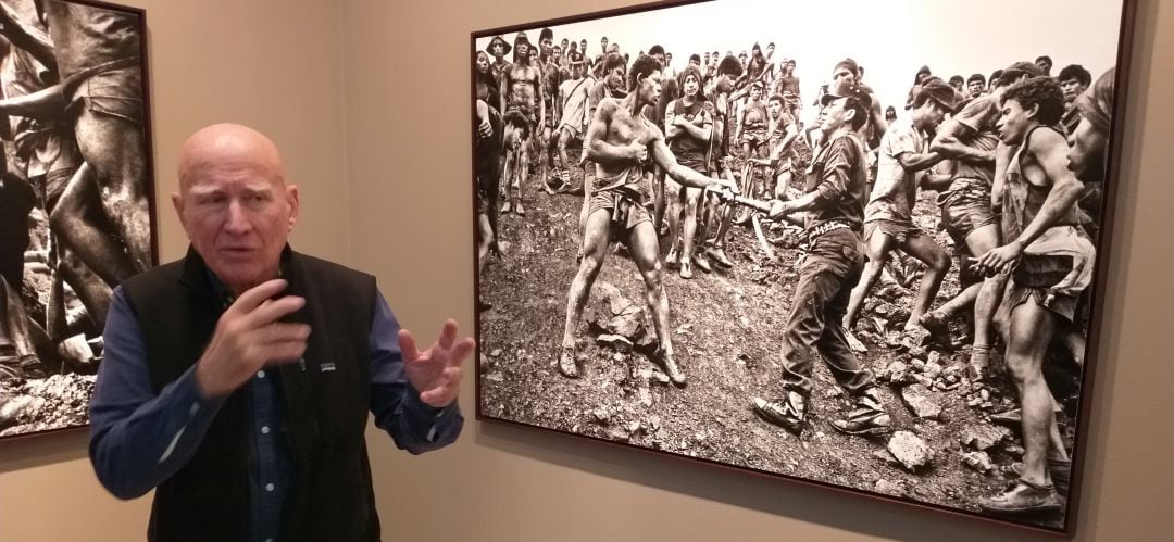 Salgado junto a una de sus fotografías explicando cómo era la vida en Serra Pelada.