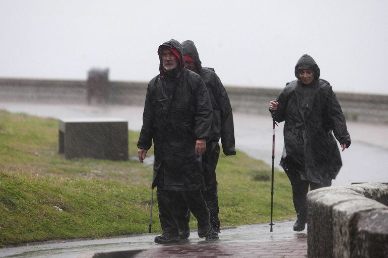 Un grupo de caminantes bajo la lluvia y el viento en cabo Silleiro, en el municipio de Baiona (Pontevedra)   