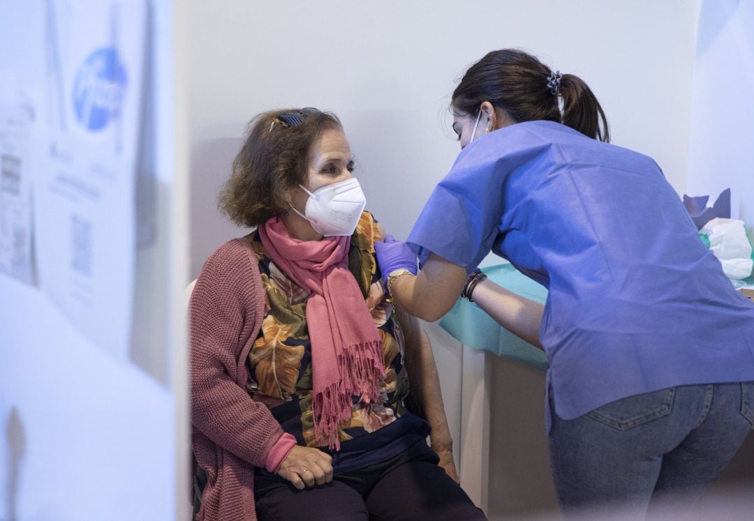 Archivo - Una sanitaria vacuna a una mujer en el Estadio de La Cartuja de Sevilla.