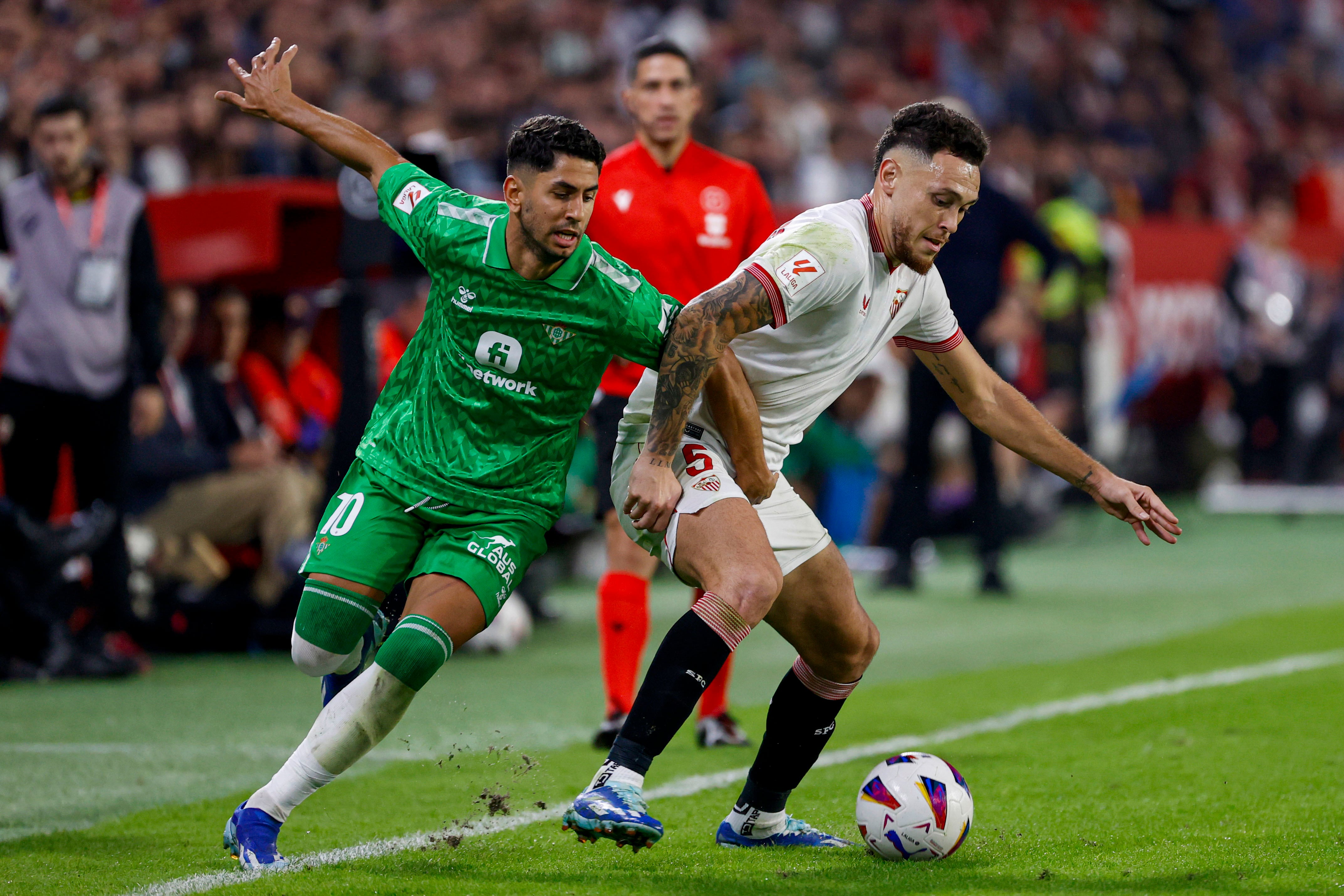 SEVILLA, 12/11/2023.- El centrocampista del Sevilla Lucas Ocampos (d) protege un balón ante Ayoze Pérez, del Betis, durante el partido de LaLiga de fútbol que Sevilla FC y Real Betis disputan este domingo en el estadio Ramón Sánchez Pizjuán. EFE/Julio Muñoz
