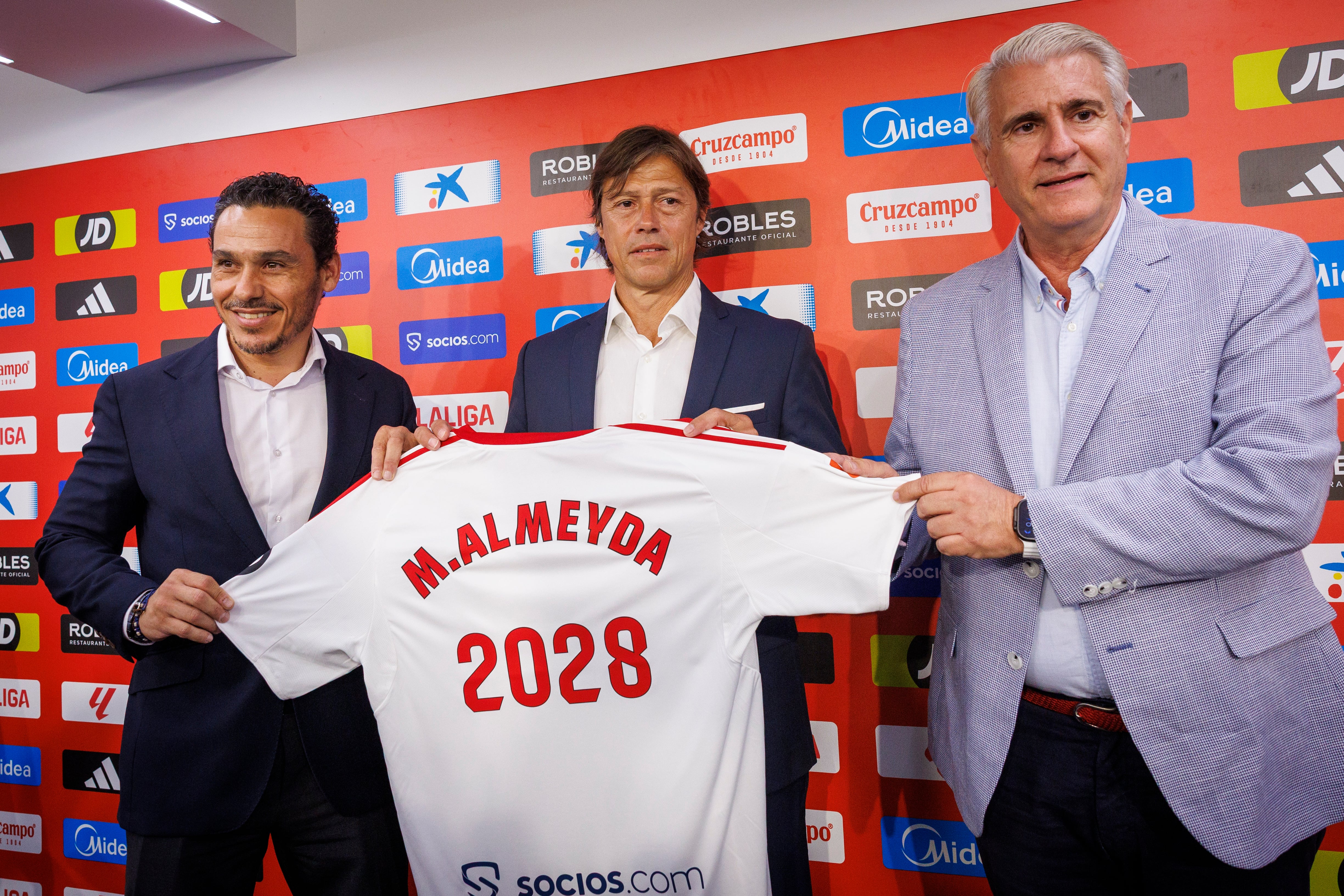 GRAFAND9934. SEVILLA, 08/07/2025.- El presidente del Sevilla, José María del Nido Carrasco (i); el argentino Matías Almeyda y el director deportivo Antonio Cordón (d), durante su presentación como nuevo entrenador del Sevilla FC, con el que ha firmado un contrato para las próximas tres temporadas y regresa casi 30 años después al club en el que ejerció como futbolista en una campaña, la 1996-1997, cuando el equipo bajó a Segunda División, este martes en la capital hispalense. EFE/ Julio Muñoz
