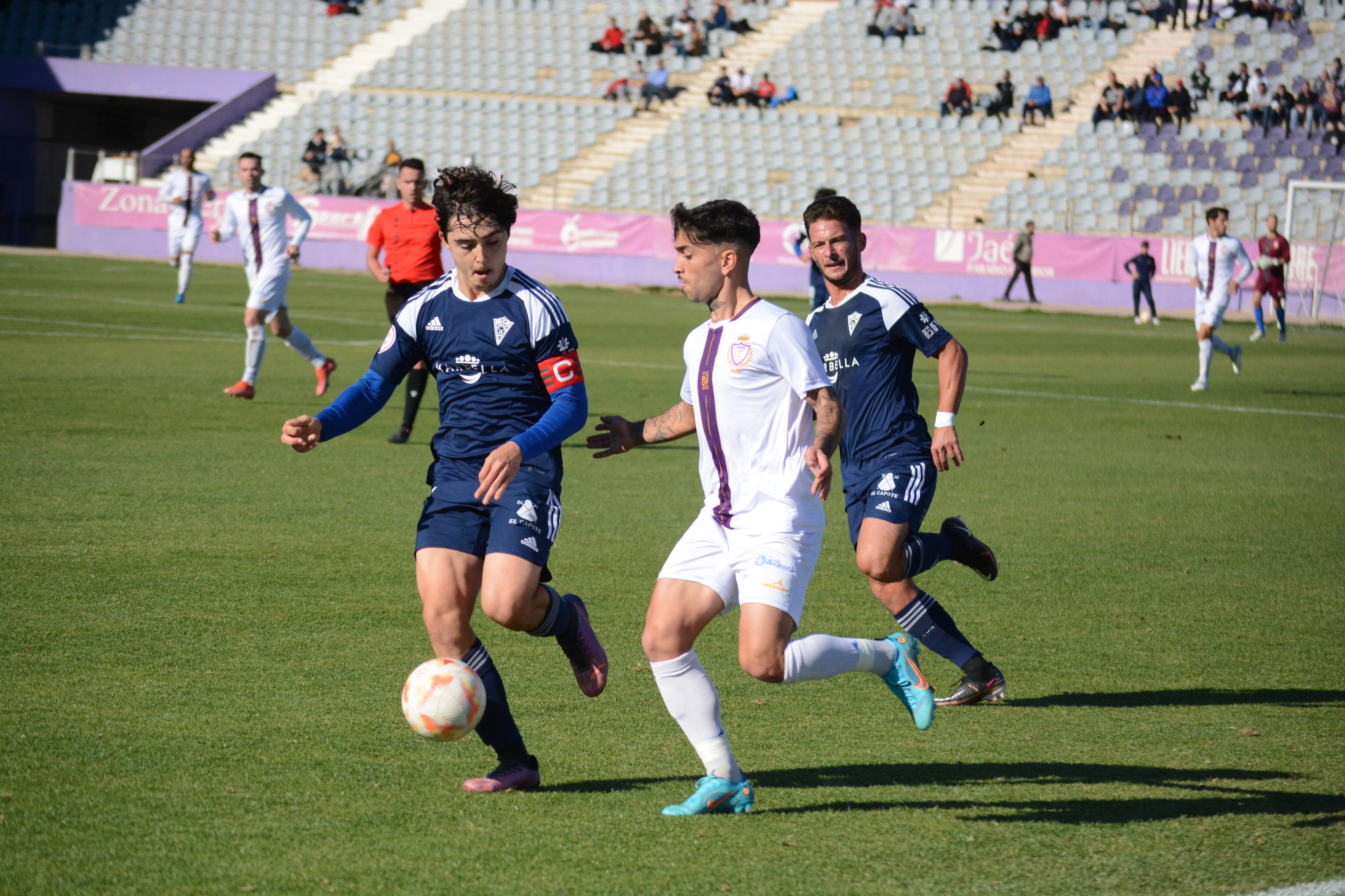 Óscar Lozano, jugador del Real Jaén entre dos defensores del Marbella, uno de ellos el capitán malagueño