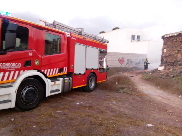 Bombero apagando el incendio de maderas en San Bartolomé.