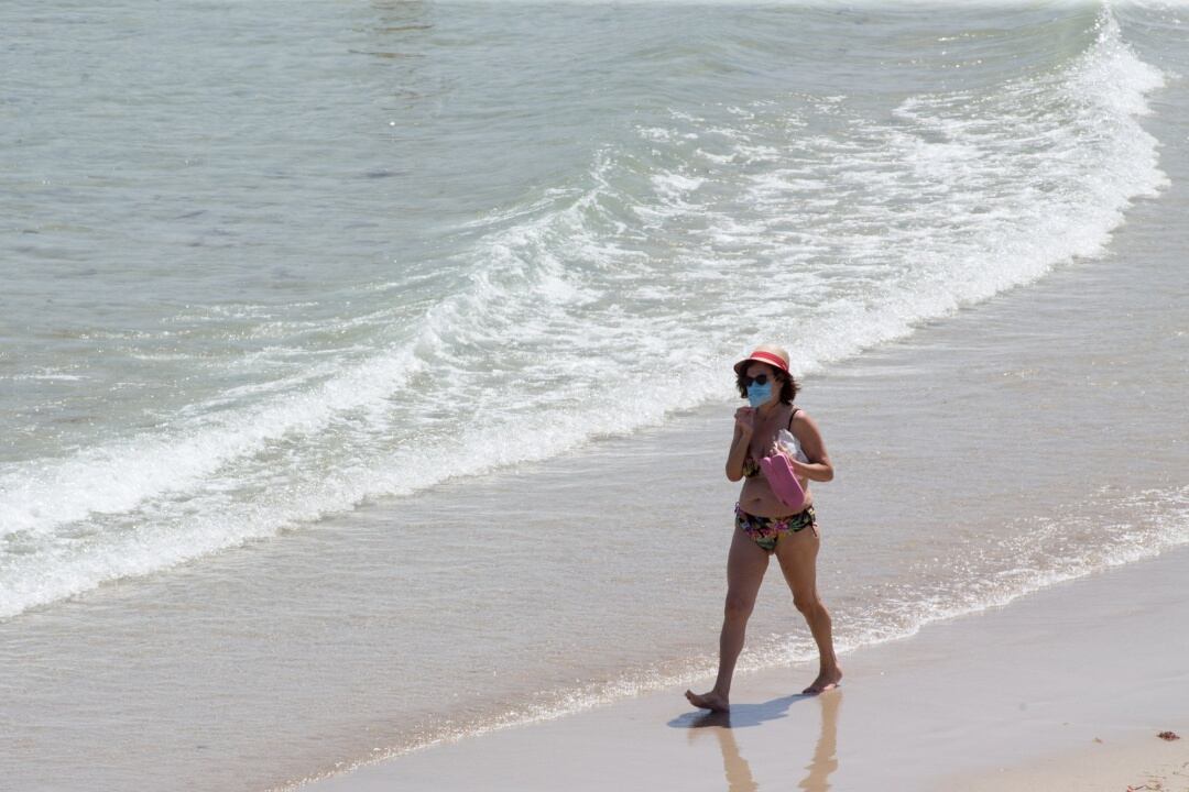 Una mujer protegida con mascarilla pasea por la Playa de A Rapadoira en Foz, en la comarca de A Mariña, Lugo