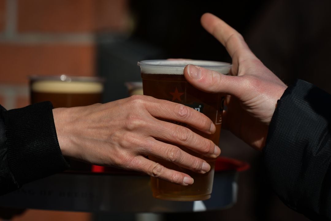 Persona cogiendo un baso de cerveza.