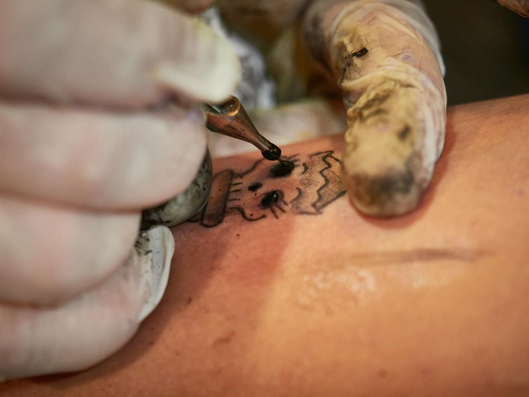 Una mujer se realiza un tatuaje. Foto de archivo. 