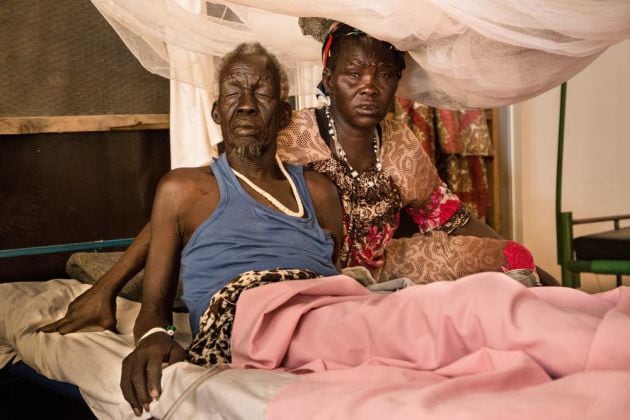 Una mujer se sienta junto a su marido, un paciente del hospital de MSF en el centro de protección civil de Malakal, en Sudán del Sur. Marzo 2019